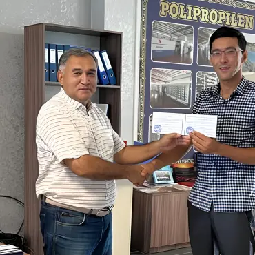Сотрудник Жаркентского крахмалопаточного завода вручает сертификат коллеге в офисе